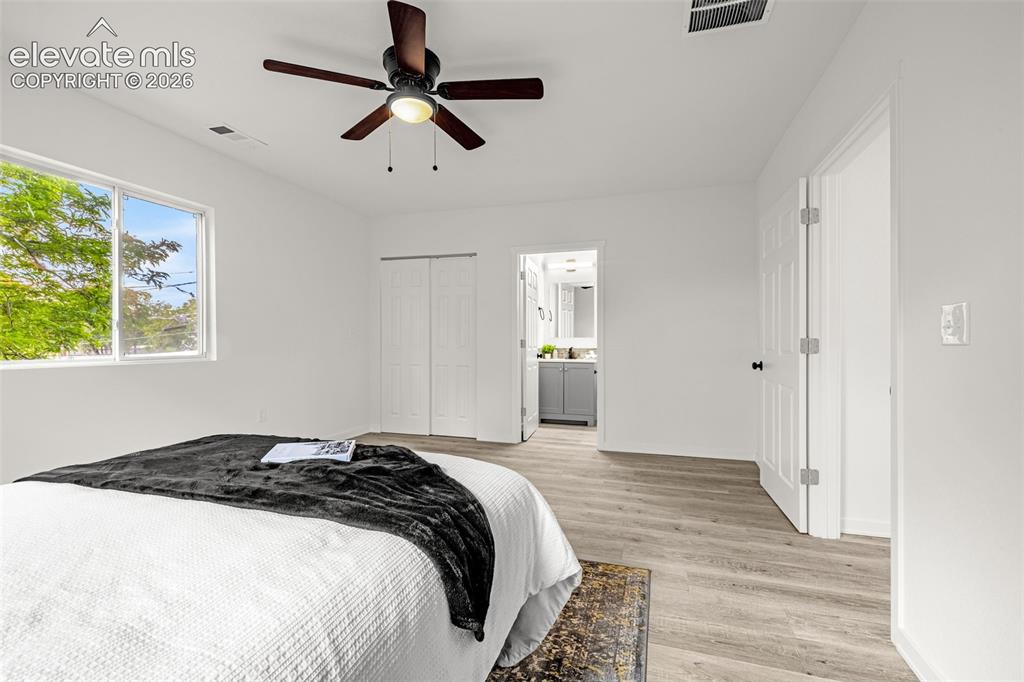 Image 12 of 50: Bedroom featuring light wood-finish flooring, white walls, and a contempora