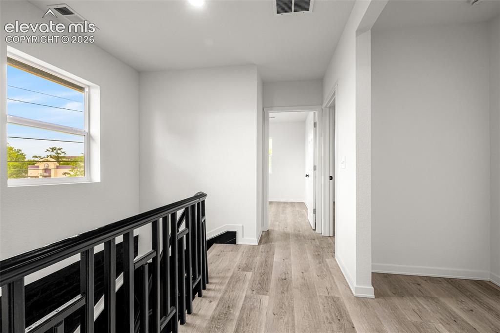 Image 21 of 50: Upper-level hallway with wood-finish flooring, white walls, and recessed li