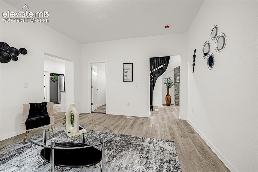 Image 24 of 50: Spacious living area featuring wood-finish flooring, white walls, and a vis
