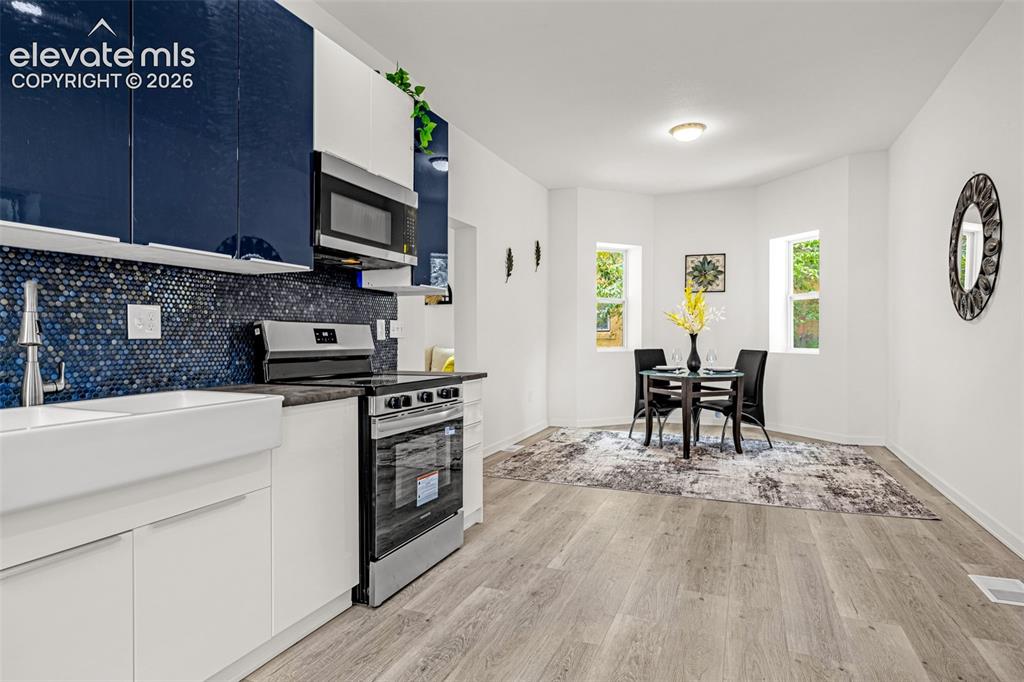 Image 28 of 50: Contemporary kitchen featuring white and navy cabinetry, a blue penny tile