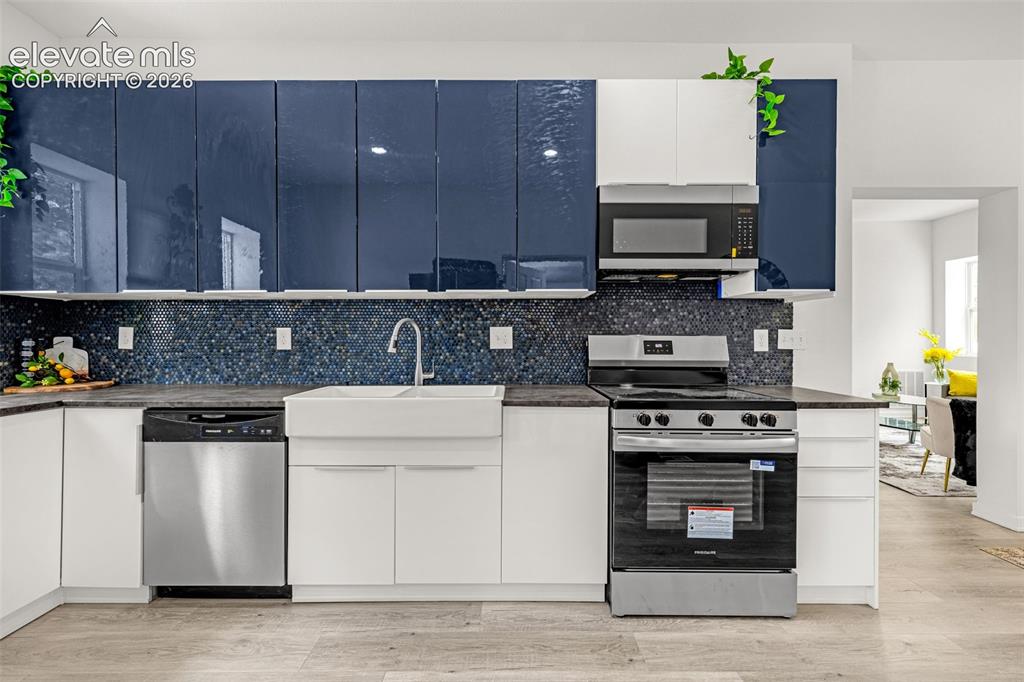 Image 30 of 50: Modern kitchen featuring gloss navy and white cabinetry, a white farmhouse