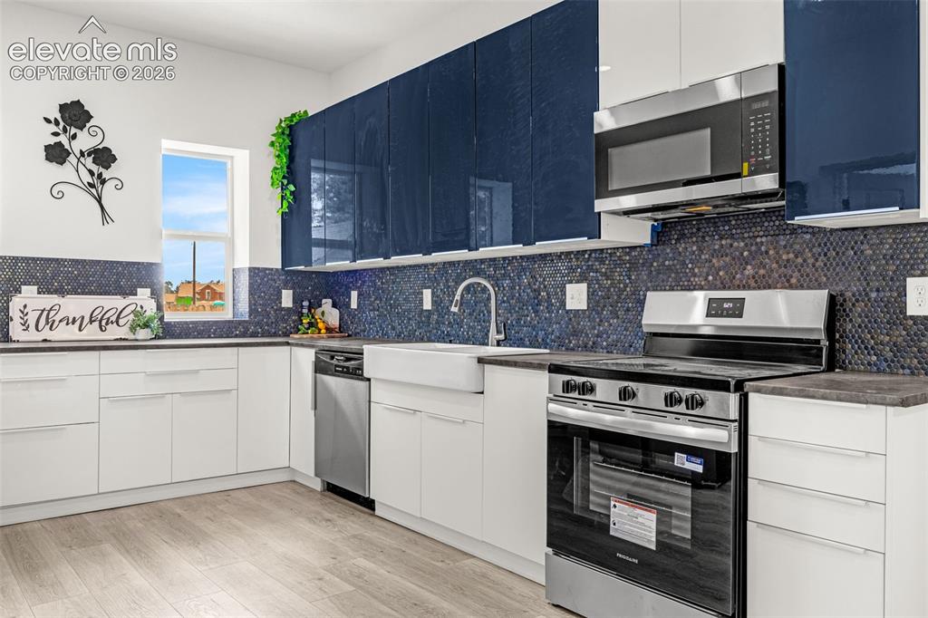 Image 32 of 50: Modern kitchen featuring wood-finish flooring and a white farmhouse sink