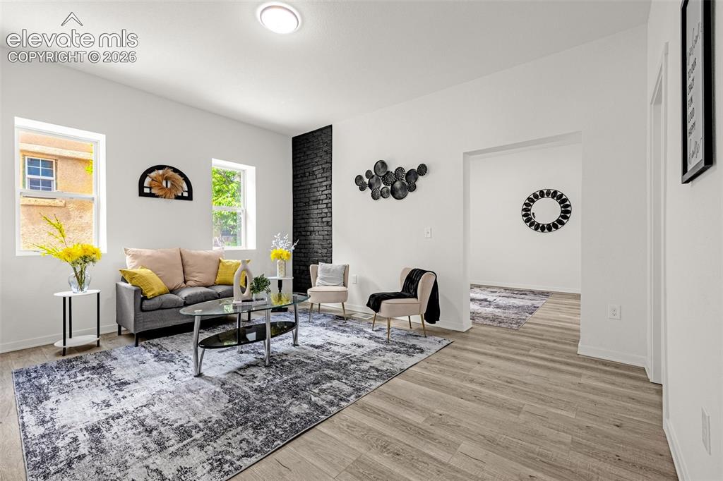 Image 37 of 50: Bright living area featuring wood-finish flooring, white walls, and a promi