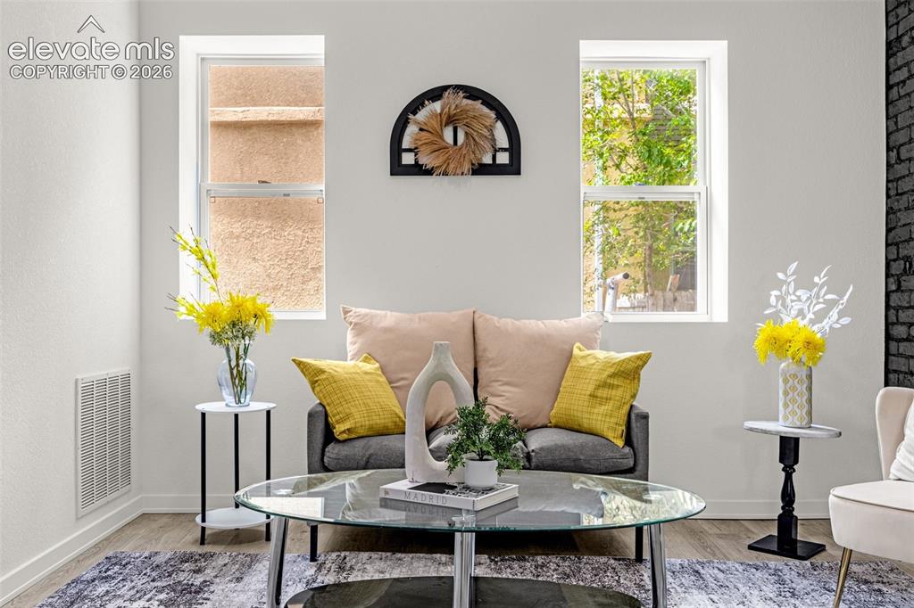 Image 38 of 50: Bright living area featuring wood-finish flooring and white walls