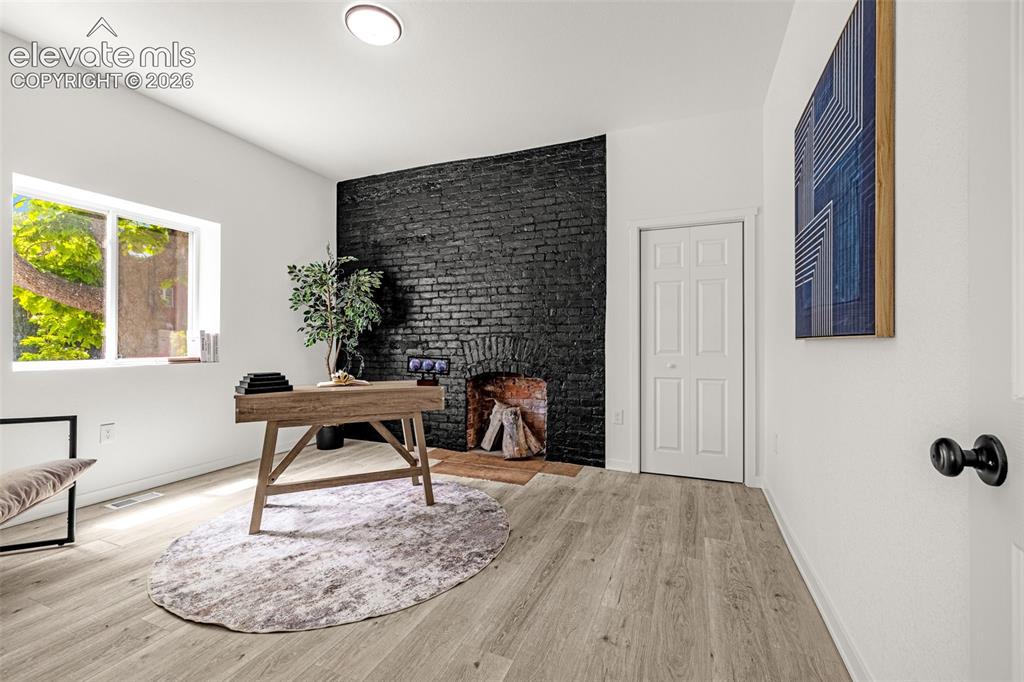 Image 4 of 50: Interior space featuring a black brick fireplace surround with a raw brick