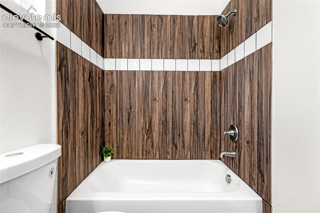 Image 6 of 50: Bathtub with wood-finish tile surround and white accent stripe