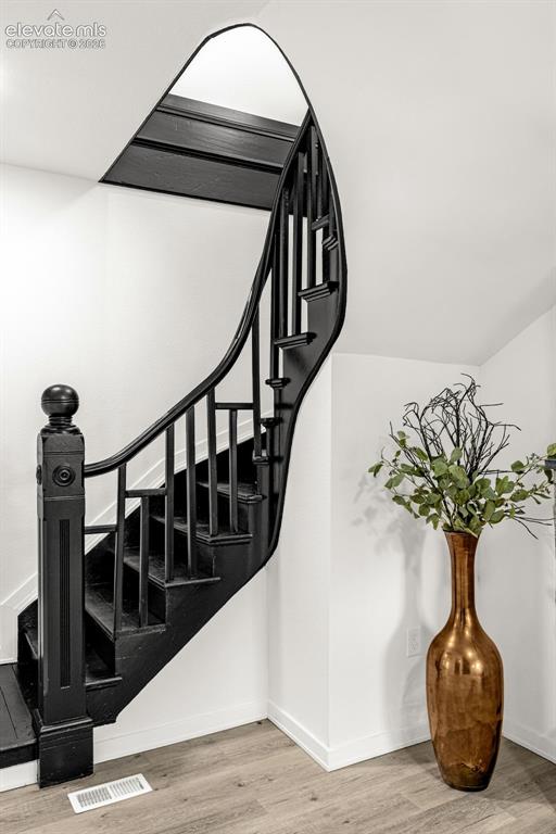 Image 7 of 50: Curved black staircase featuring a substantial newel post, balusters, and h