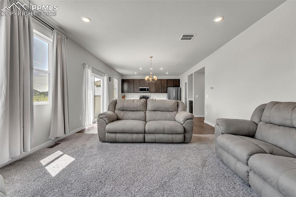 Image 13 of 50: Living area with a chandelier, recessed lighting, and light carpet