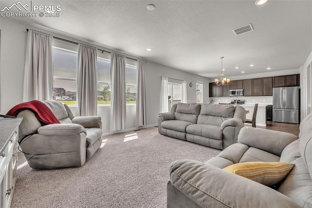 Image 14 of 50: Living room featuring recessed lighting, a chandelier, light carpet, and a 