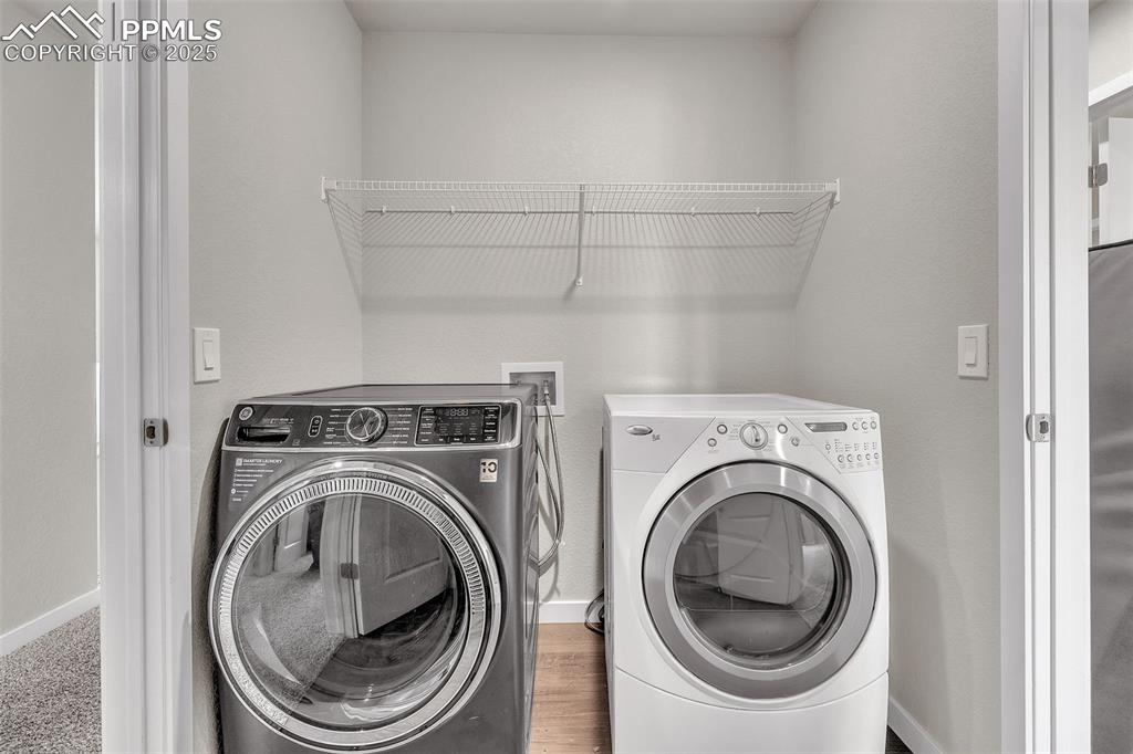 Image 38 of 50: Laundry room with washer and clothes dryer and wood finished floors