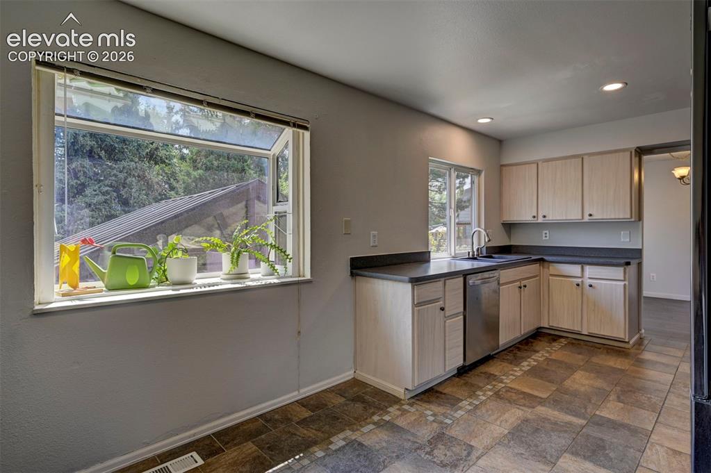 Image 17 of 49: Kitchen featuring wood-finish cabinetry, stainless steel dishwasher, and re