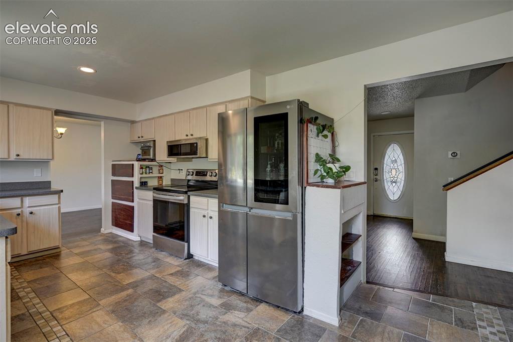 Image 18 of 49: Kitchen featuring light wood-finish cabinetry, stainless steel appliances,