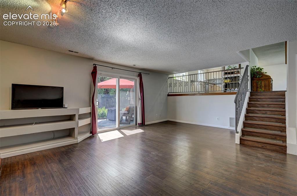 Image 19 of 49: Wood-finish flooring, built-in entertainment shelving, sliding glass door t