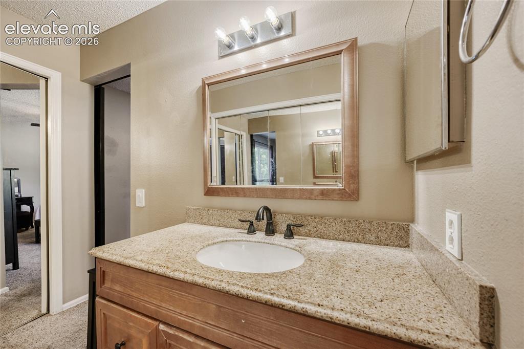 Image 21 of 49: Vanity with a built-in sink, dark-toned faucet, and a light-toned counterto