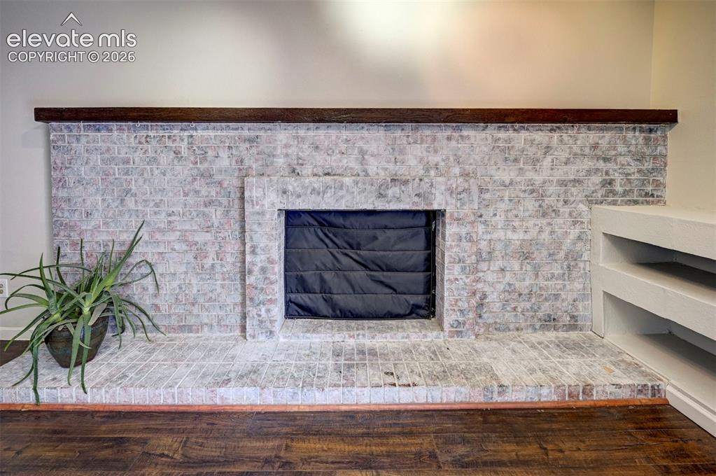 Image 22 of 49: Whitewashed brick fireplace with a dark wood mantel and wood-finish floorin