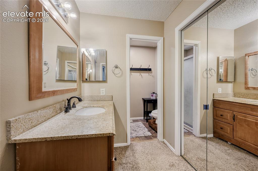 Image 23 of 49: Bathroom featuring dual vanities with granite-style countertops, wood-finis