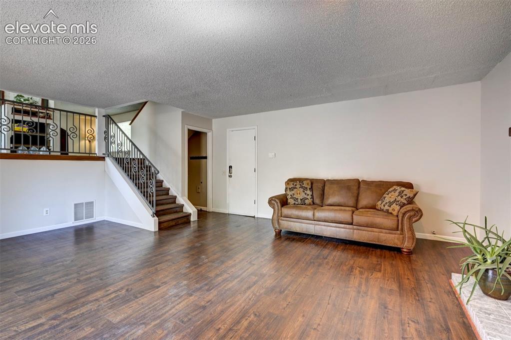 Image 24 of 49: Wood-finish flooring throughout, featuring a staircase with wrought iron ba