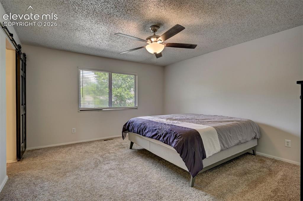 Image 26 of 49: Barn door entry, ceiling fan with integrated lighting, window with horizont