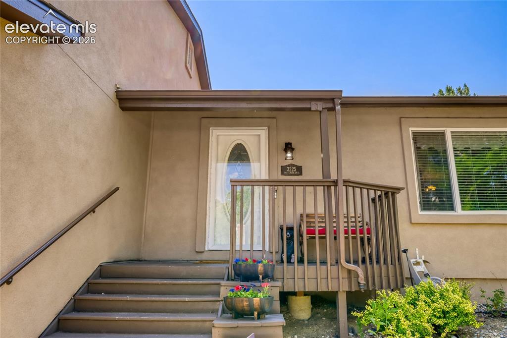 Image 3 of 49: Stucco exterior with a covered porch featuring a wood railing