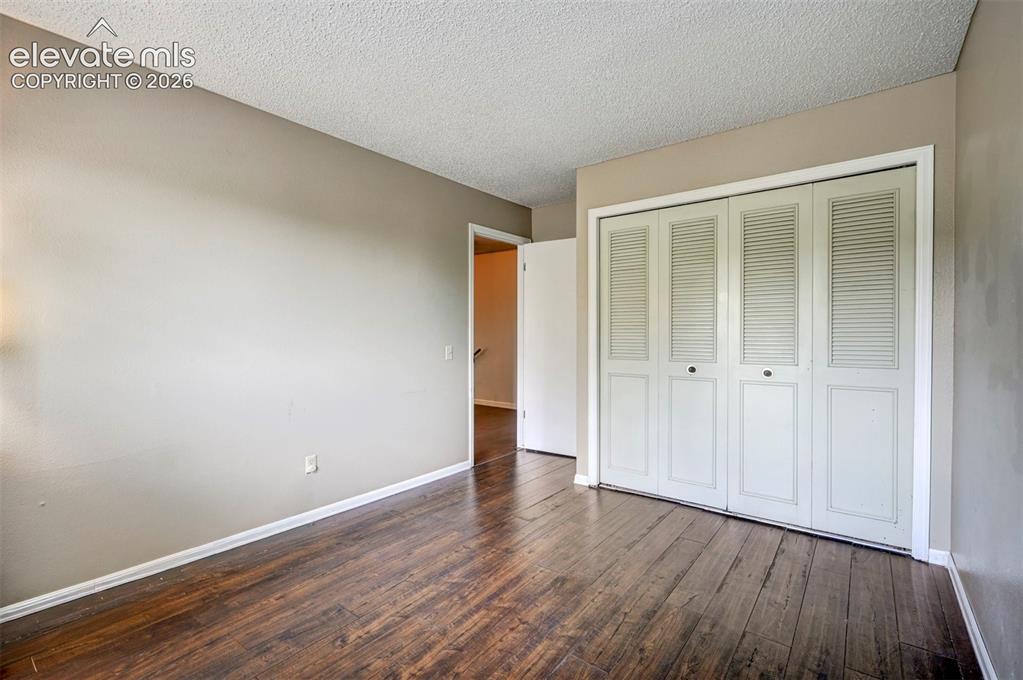 Image 33 of 49: Wood-finish flooring, neutral wall color, and bi-fold louvered closet doors
