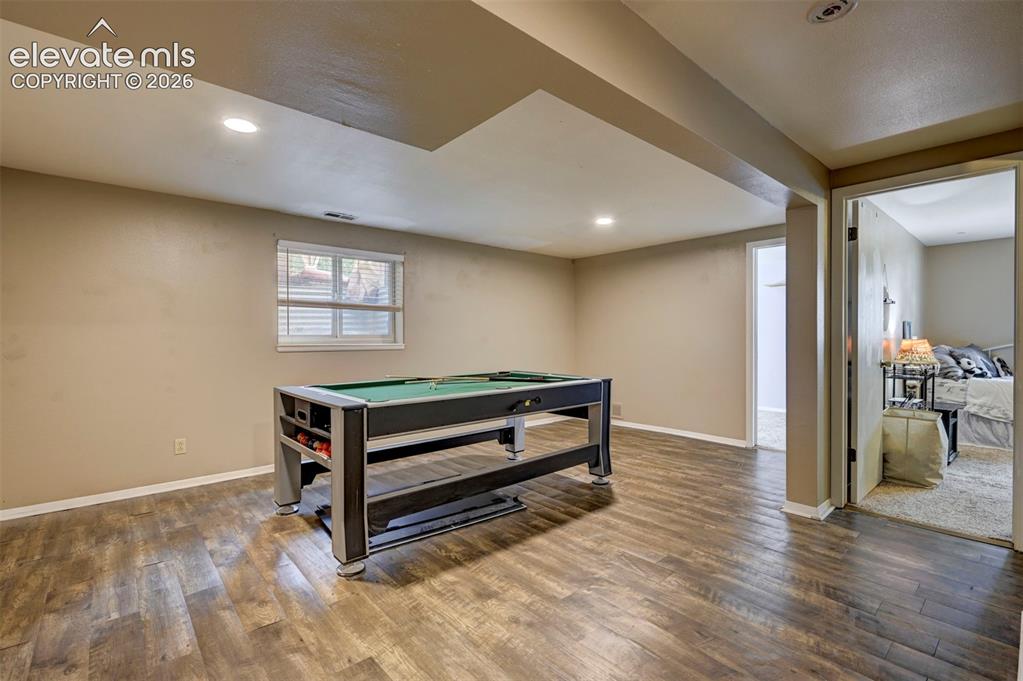 Image 37 of 49: Recessed lighting, wood-finish flooring, and a window with blinds