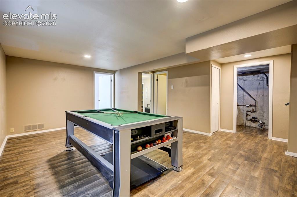 Image 38 of 49: Recessed lighting illuminates the wood-finish flooring and neutral wall ton