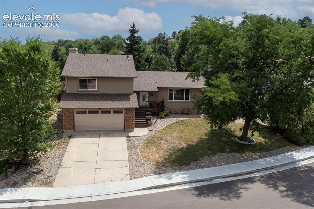 Image 4 of 49: Two-story exterior with a two-car garage, brick facade, and a paved drivewa