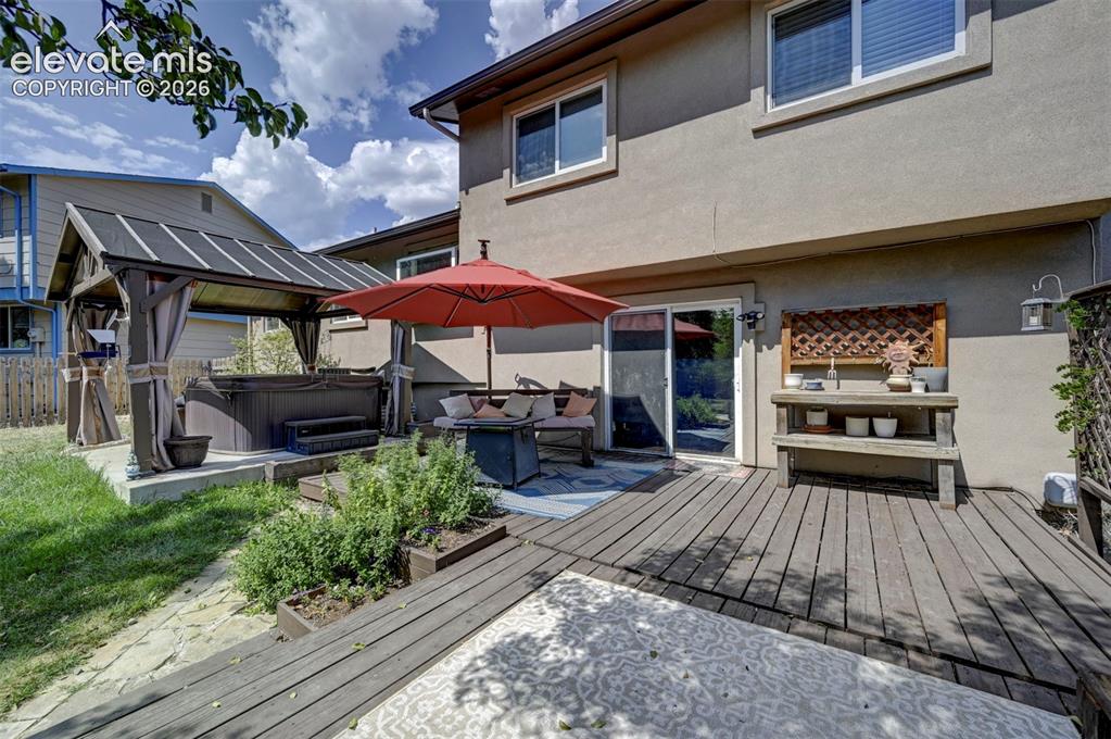 Image 46 of 49: Expansive rear deck with wood-finish planks, built-in planters, sliding gla