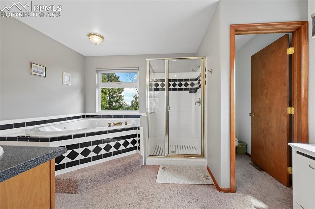 Image 10 of 25: Bathroom featuring a corner soaking tub with black and white tile surround,