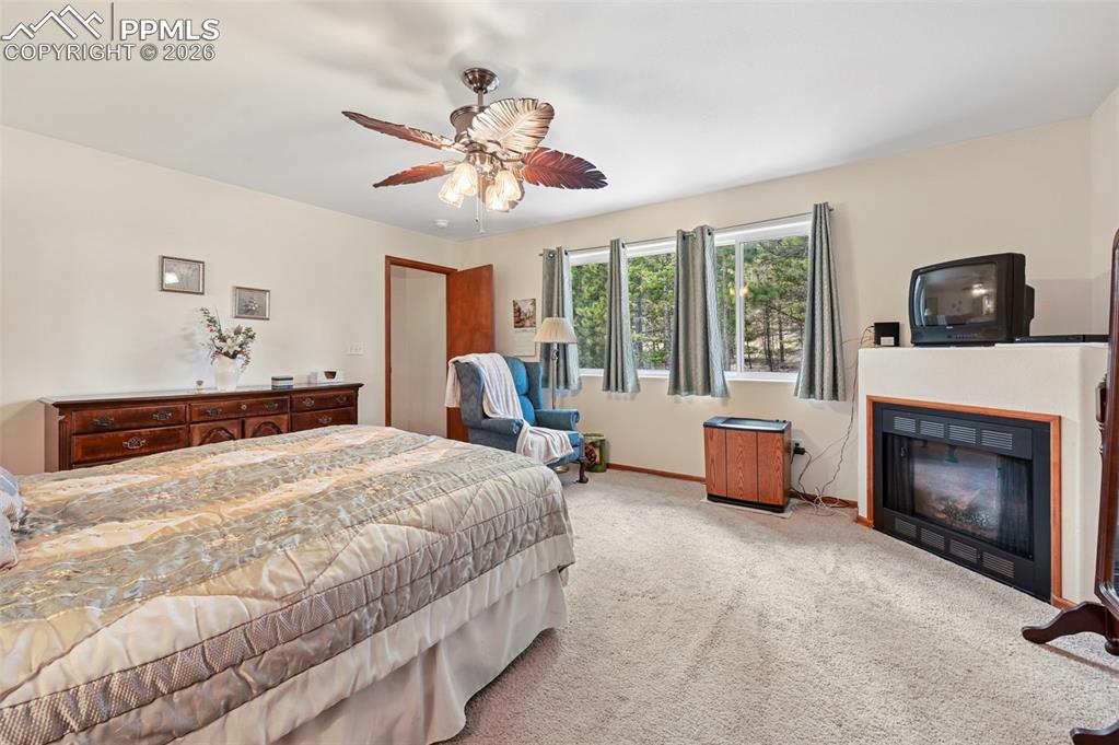 Image 11 of 25: Carpeted bedroom featuring a built-in fireplace with a wooden surround and 
