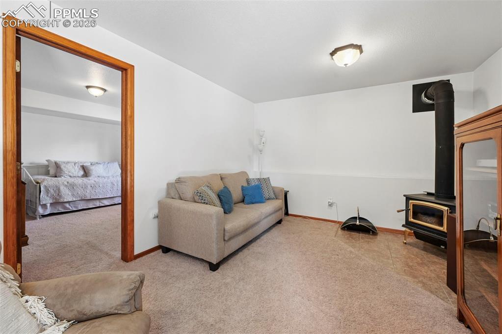 Image 16 of 25: Living area featuring a freestanding wood-burning stove with a black stovep