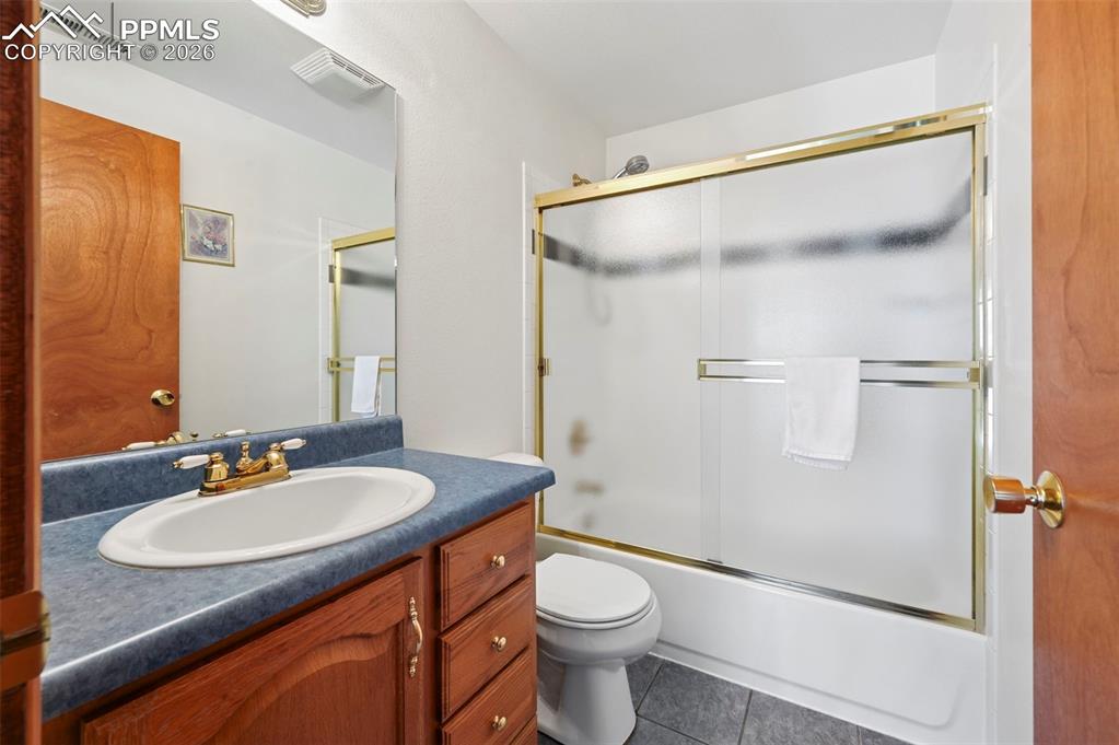 Image 21 of 25: Bathroom featuring a wood-finish vanity with a blue countertop, an oval und