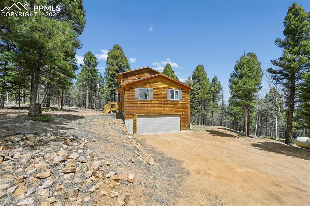 Image 24 of 25: Rustic wood-sided exterior featuring a two-car garage