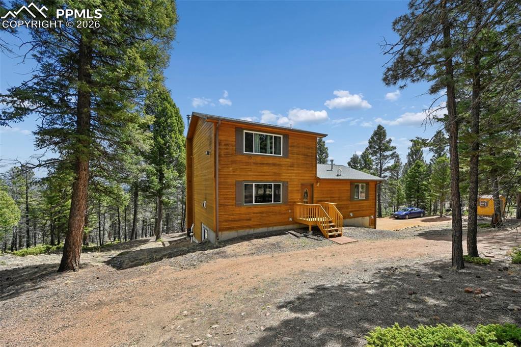 Image 25 of 25: Wood-sided residence surrounded by mature evergreen trees