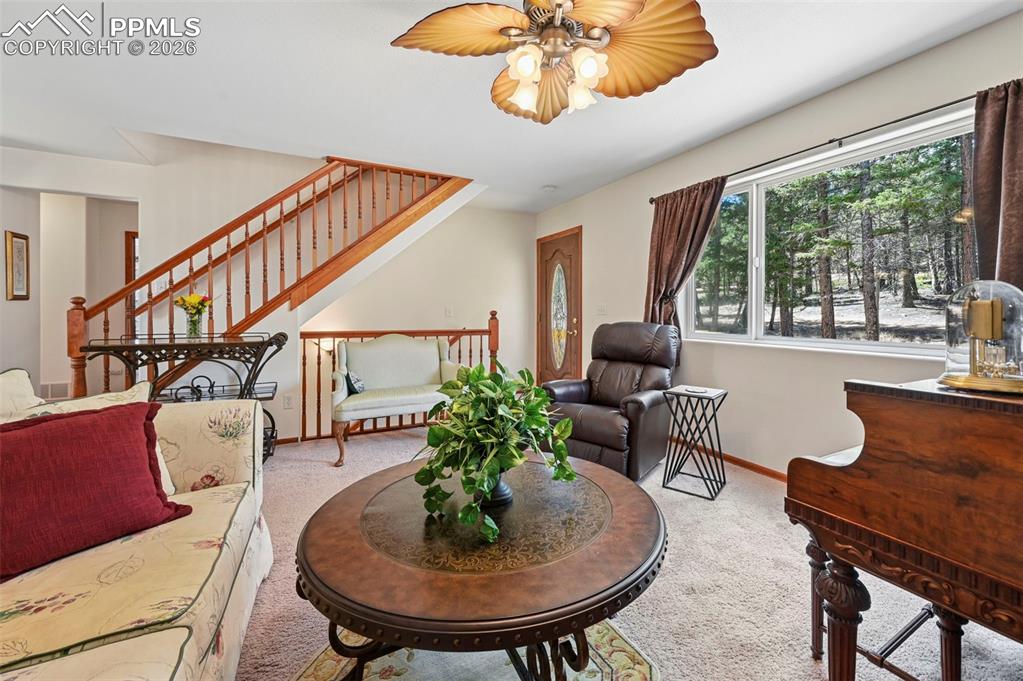 Image 8 of 25: Living area featuring a prominent staircase with wood railings, a window wi