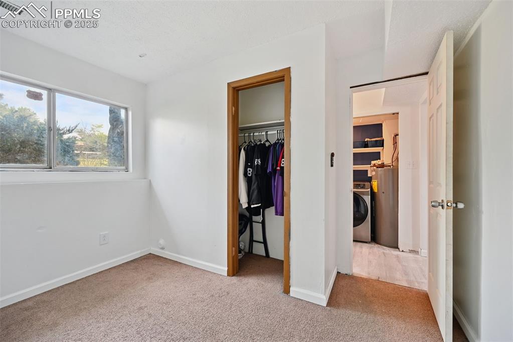 Image 12 of 19: Unfurnished bedroom with carpet, water heater, washer / dryer, and a spacio