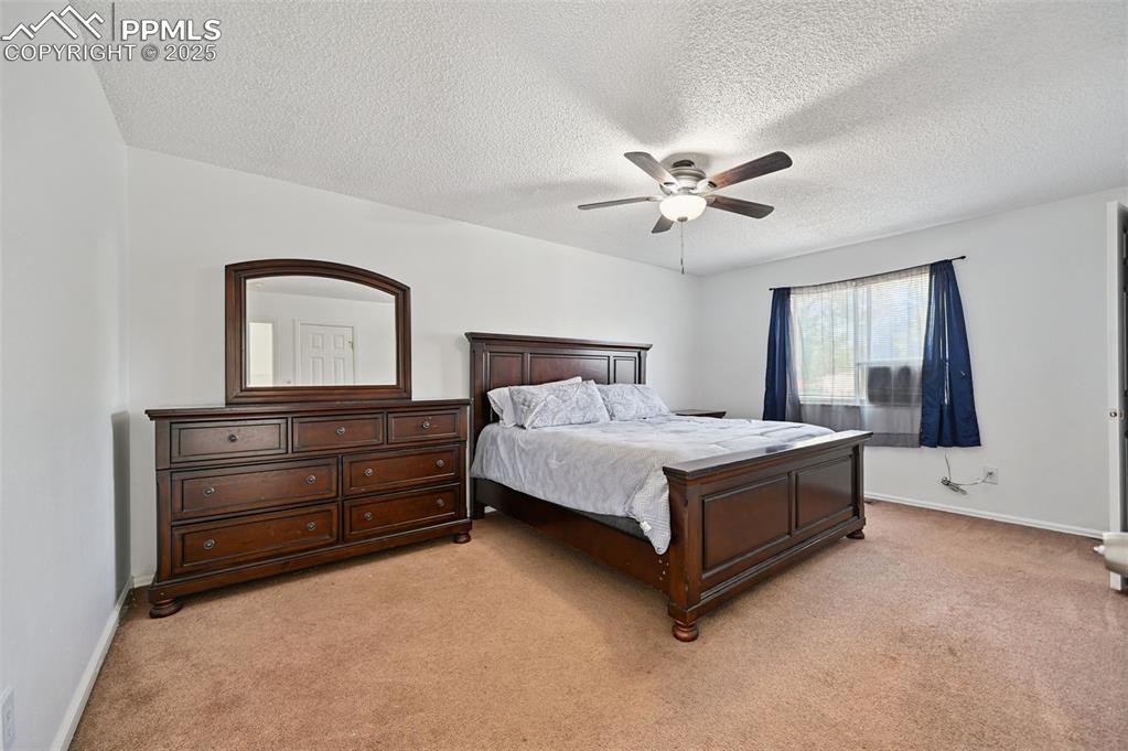 Image 13 of 19: Bedroom featuring light colored carpet, a textured ceiling, and a ceiling f