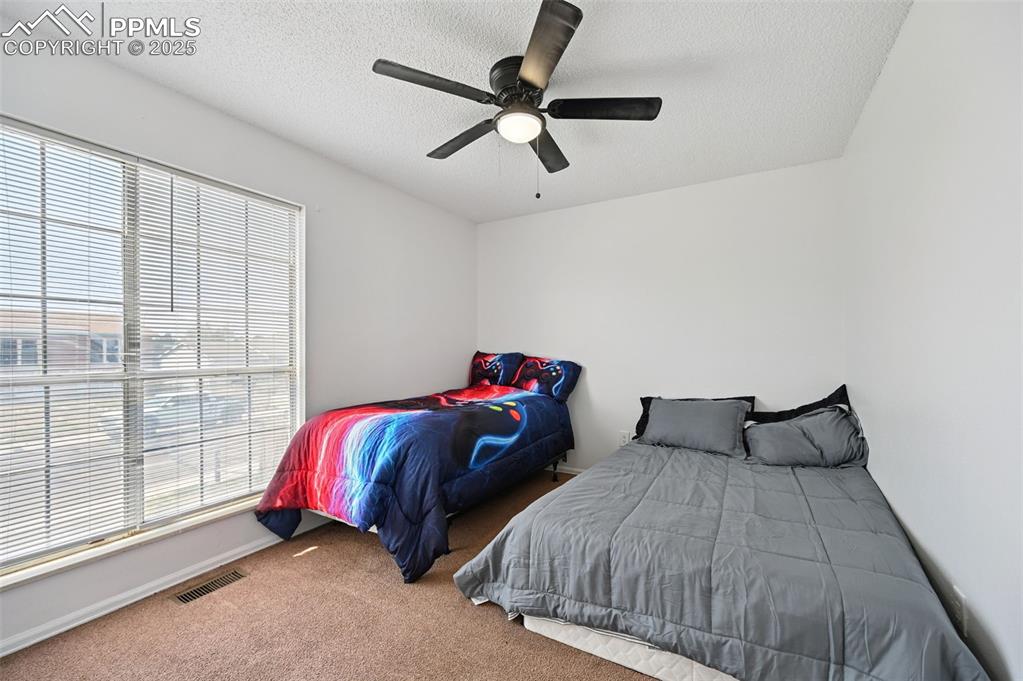 Image 14 of 19: Carpeted bedroom featuring a textured ceiling and ceiling fan