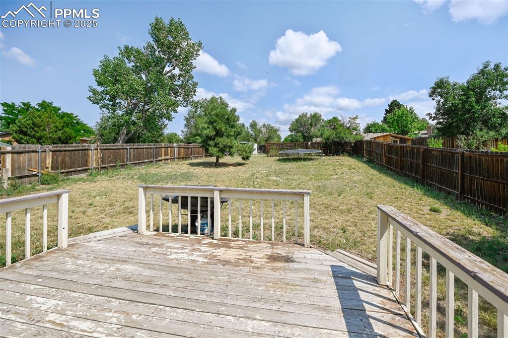Image 16 of 19: Wooden terrace featuring a trampoline and a fenced backyard