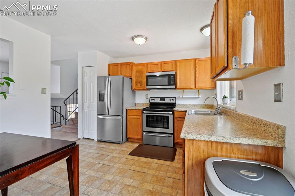 Image 4 of 19: Kitchen with stainless steel appliances, light countertops, and brown cabin