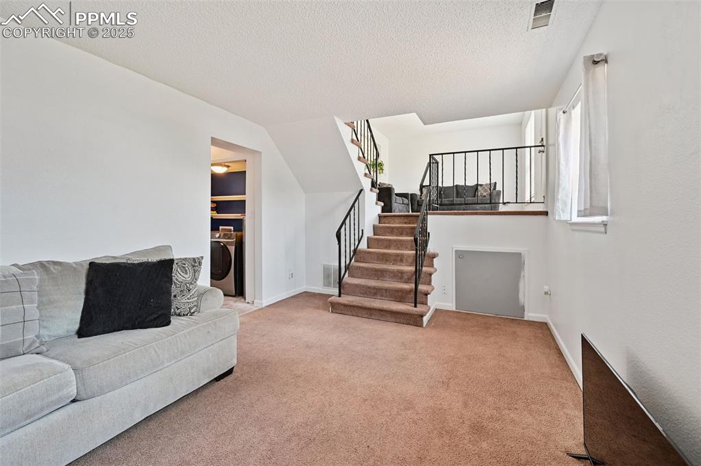 Image 8 of 19: Living area with a textured ceiling, carpet flooring, washer / dryer, and s