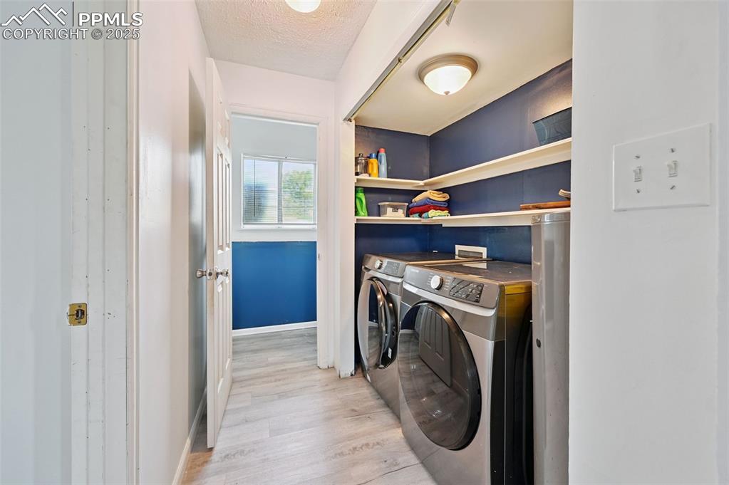 Image 9 of 19: Laundry area featuring washing machine and clothes dryer, a textured ceilin