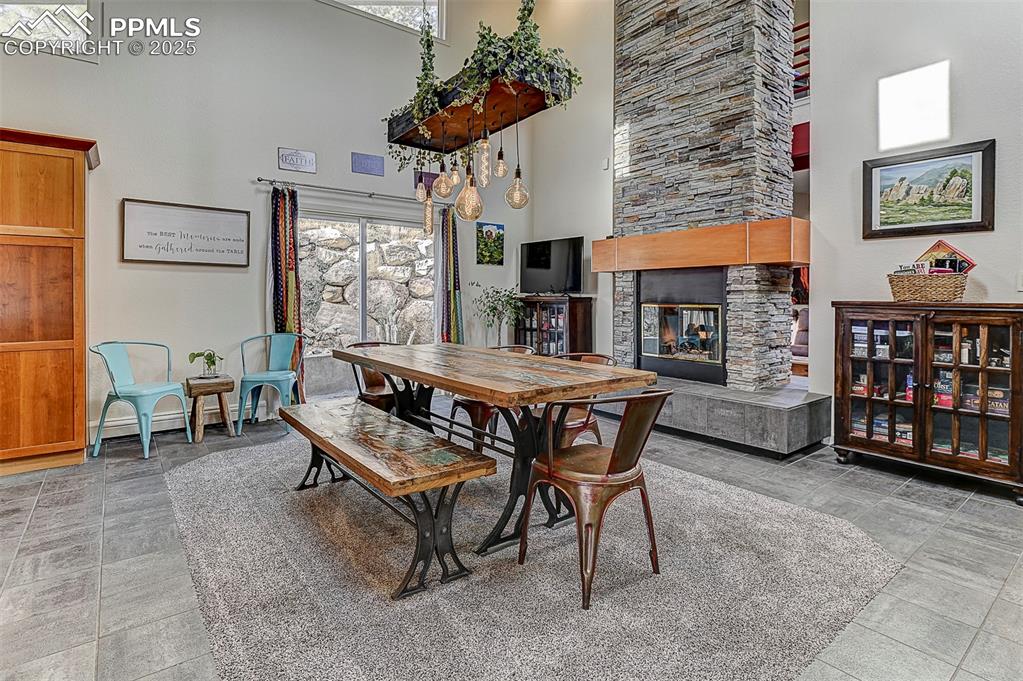 Image 14 of 42: Dining space with a stone fireplace and a towering ceiling