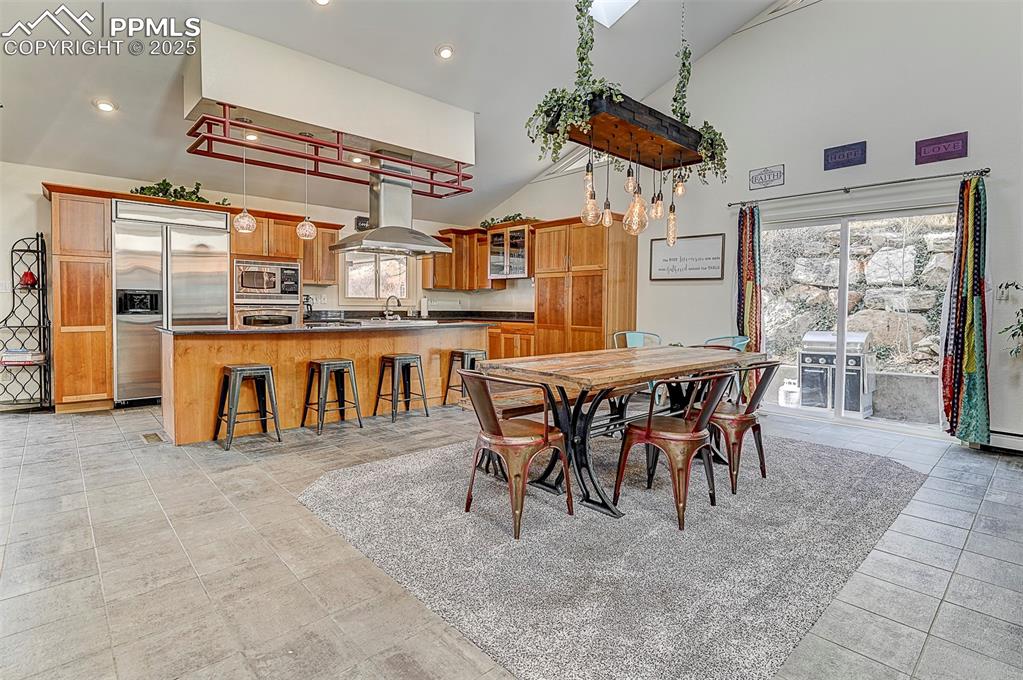 Image 15 of 42: Dining & kitchen space featuring high vaulted ceiling and recessed lighting