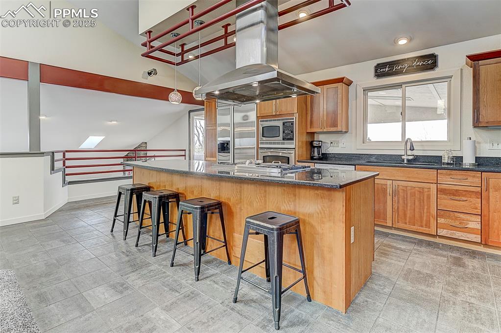 Image 19 of 42: Kitchen with quartz island, range hood, a breakfast bar, and built in luxe
