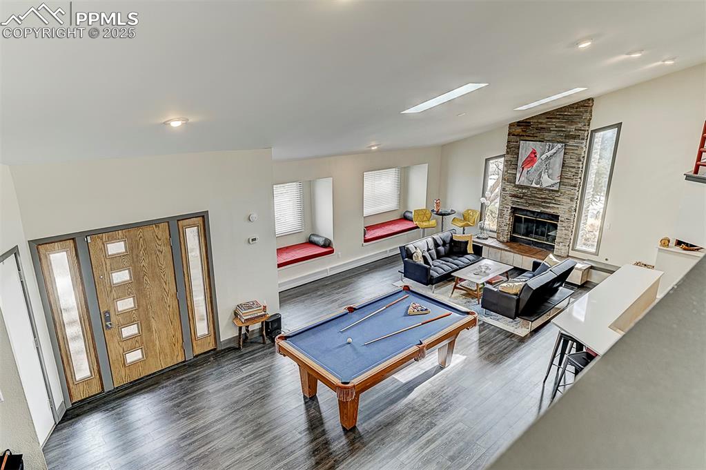 Image 22 of 42: View from living/dining/kitchen to family room below with a stone fireplace
