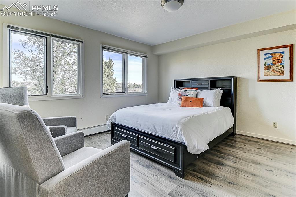 Image 25 of 42: Bedroom 2- main level featuring wood finished floors, baseboard heating