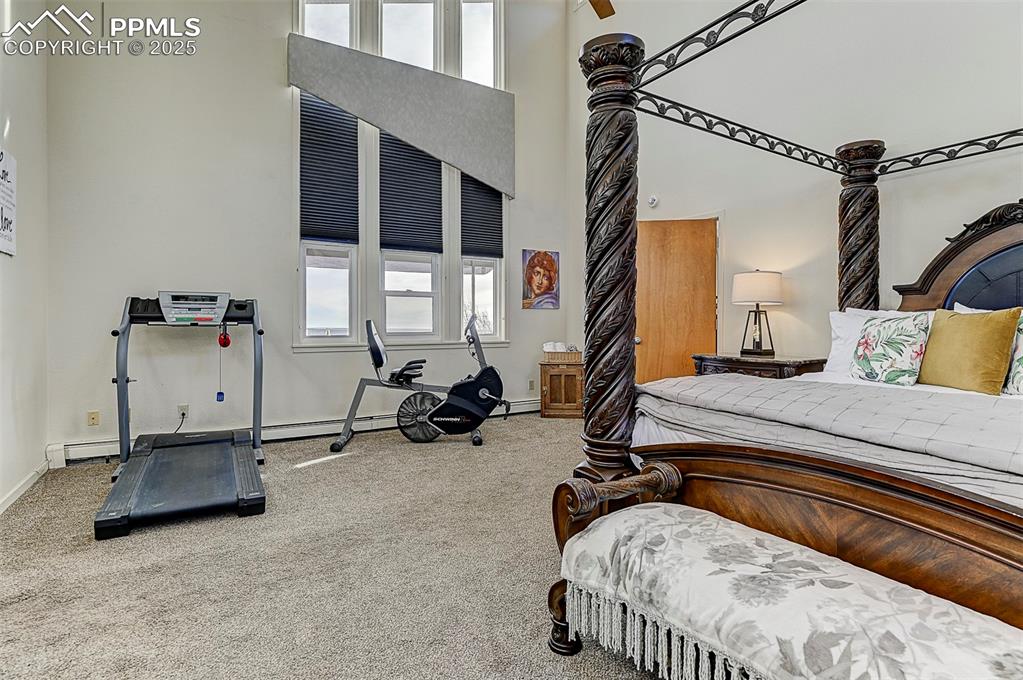 Image 31 of 42: Carpeted bedroom featuring a towering ceiling and a ceiling fan