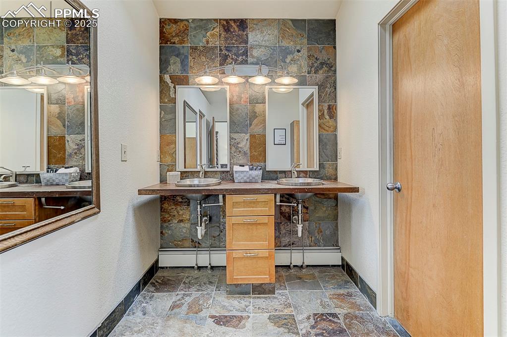 Image 32 of 42: Full bath featuring slate tile floors, slate accents and double vanity