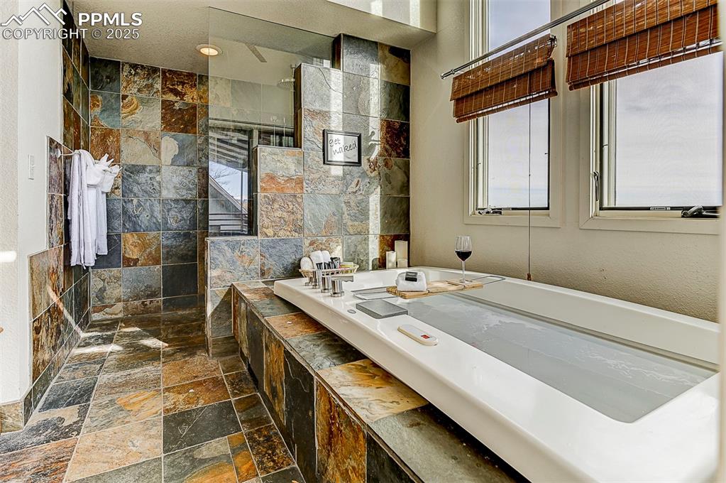 Image 34 of 42: Bathroom suite featuring walk in shower and spa like tub with views for mil
